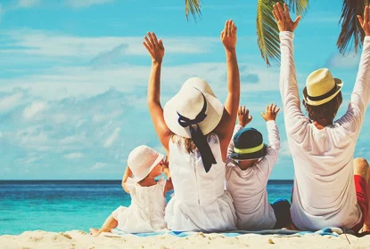 Happy family enjoying beach vacation raising hands toward ocean
