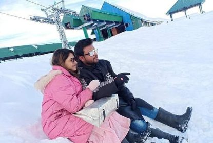 Couple enjoying snow adventure sitting together at Gulmarg ski resort in Kashmir during winter vacation