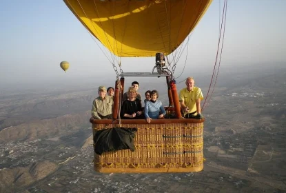 Tourists enjoying hot air balloon ride above city skyline during sunrise