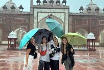 Tourists holding umbrellas posing at Taj Mahal entrance gate during rainy day in Agra India