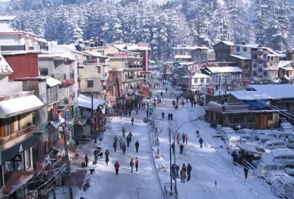 Snow-covered Manali Mall Road with tourists walking and shops lined along scenic street